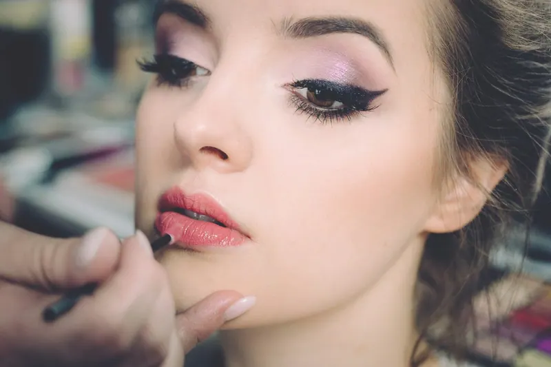 Makeup artist applying lipstick to a client