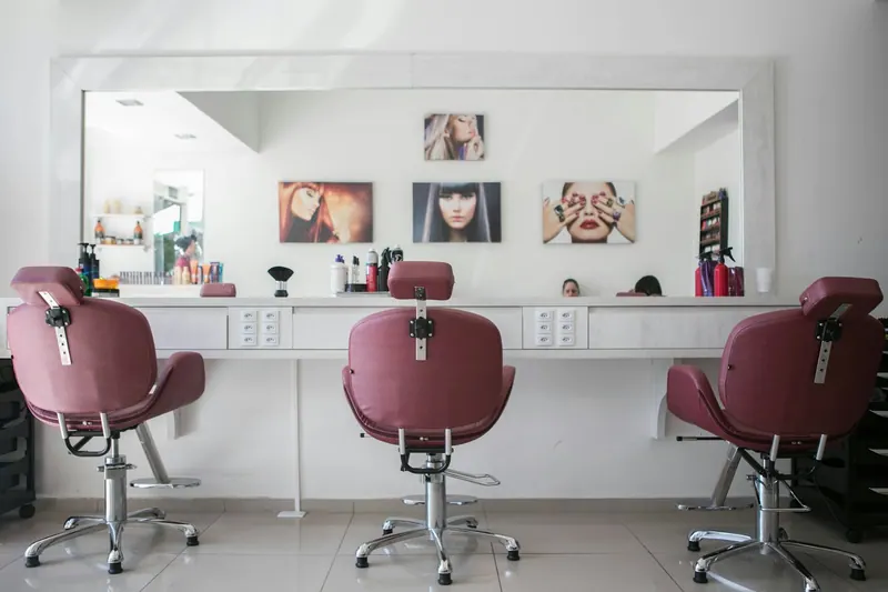 Pink salon styling chairs facing a long mirror