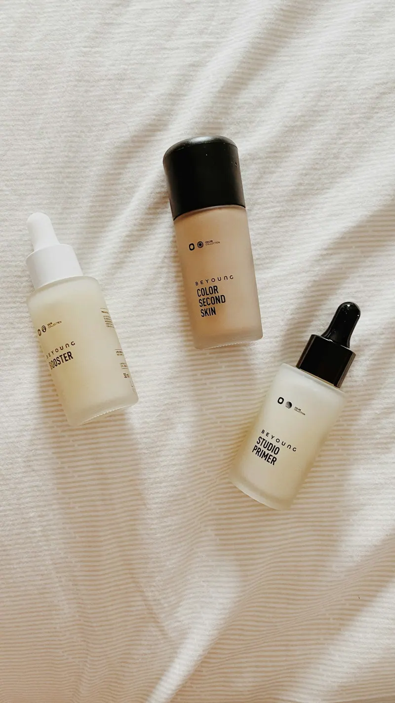 Skincare serum and foundation bottles on white linen